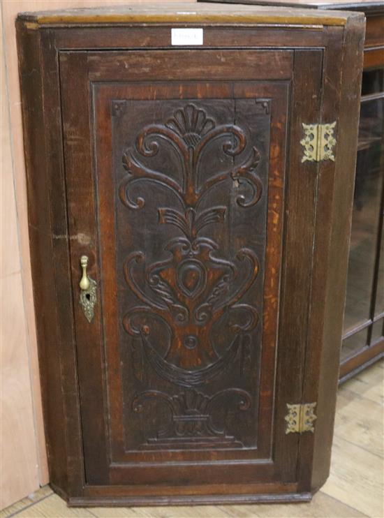 A late 18th century later carved oak corner cupboard